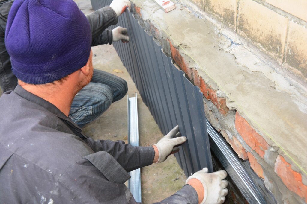 Men working on old house foundation wall repair