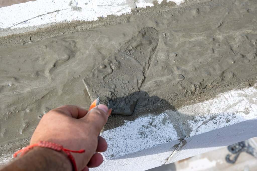 hand holding cement spatula to finish slab foundation repair | guide to slab foundation repair for home