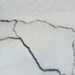 Severe wide branching cracks in a concrete foundation surface indicating major structural movement and damage