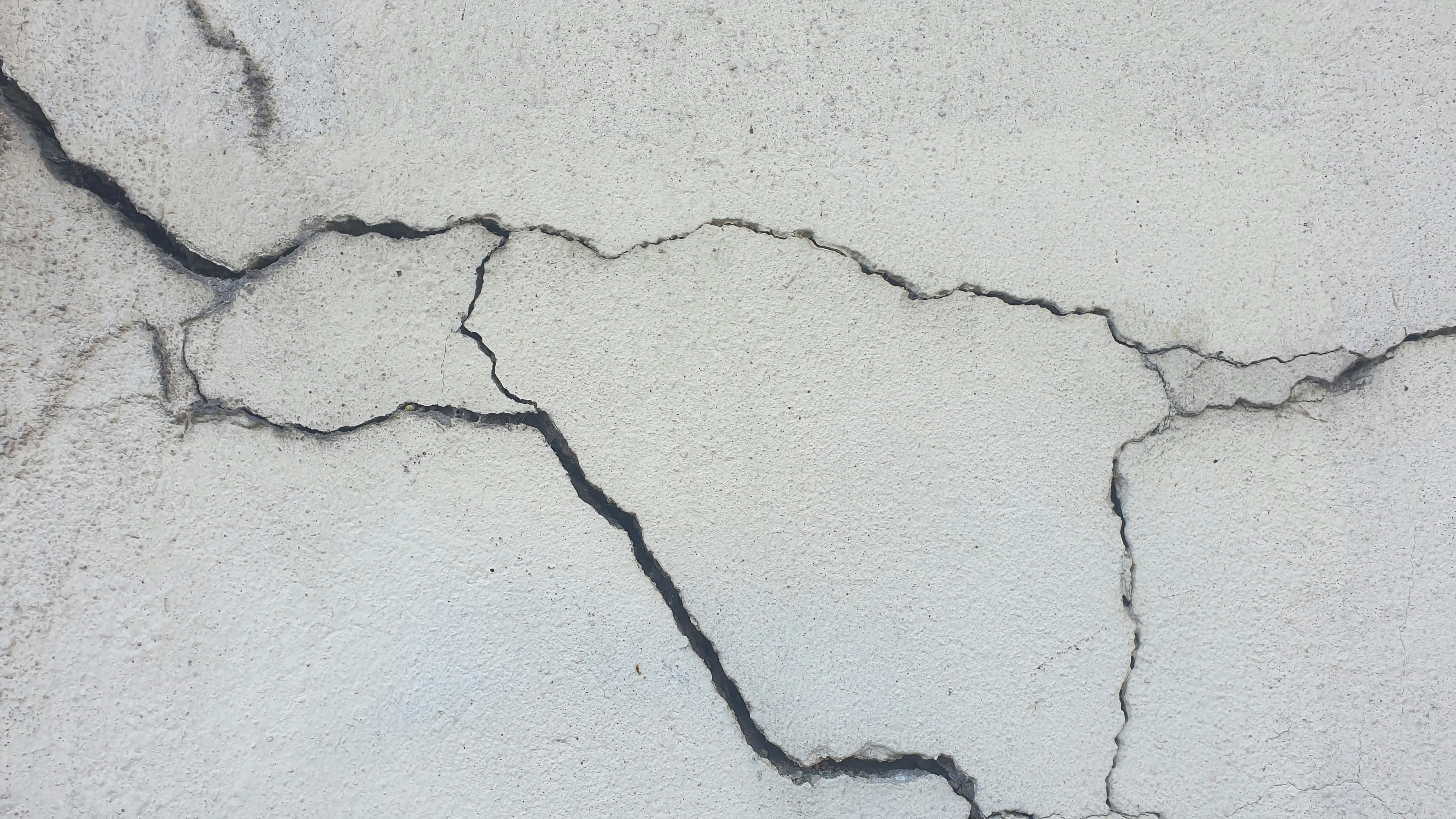 Severe wide branching cracks in a concrete foundation surface indicating major structural movement and damage