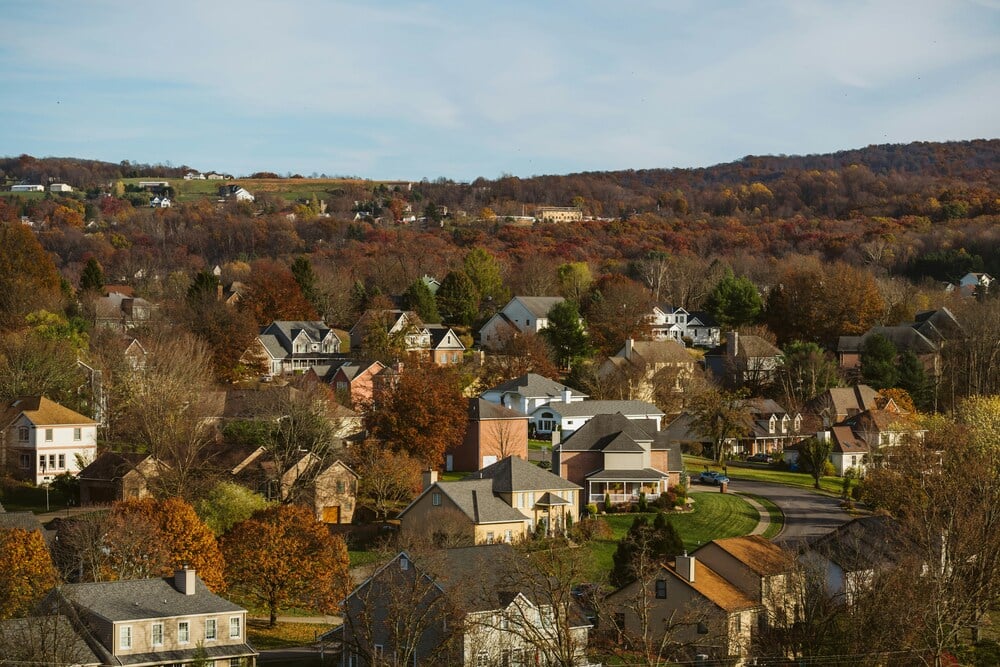 A high-angle view looking down over a North Texas suburban neighborhood with rolling hills in the background.