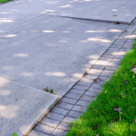 Residential concrete driveway with joints and edging near a lawn.