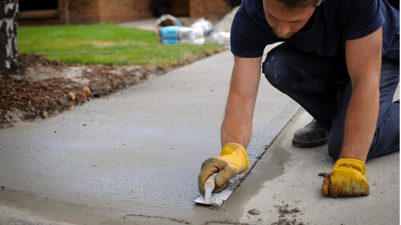 Contractor smoothing fresh concrete during a residential repair project.