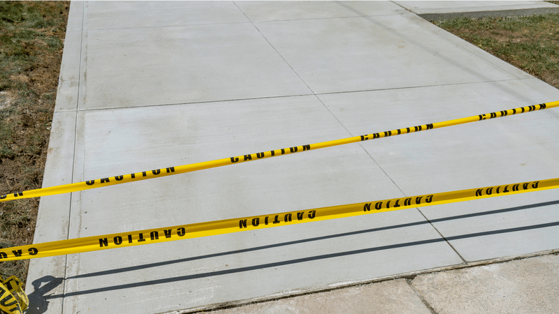 Newly poured concrete section blocked off with caution tape during curing.