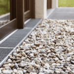 Surface drain and gravel installed beside a home to move water away from the foundation.