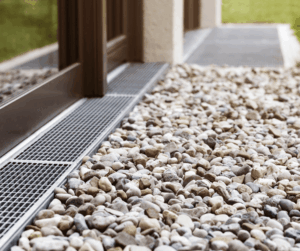 Surface drain and gravel installed beside a home to move water away from the foundation.