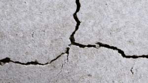 Wide branching crack spreading across a concrete foundation wall, the kind of structural damage that signals serious movement below.